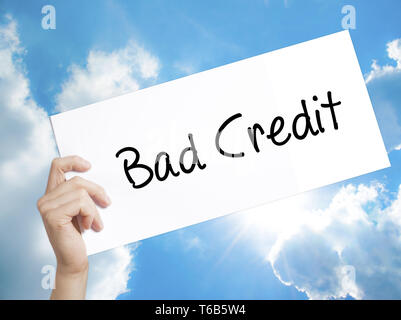 Bad Credit Sign on white paper. Man Hand Holding Paper with text. Isolated on sky background Stock Photo
