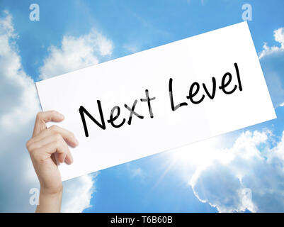 Next Level Sign on white paper. Man Hand Holding Paper with text. Isolated on sky background Stock Photo