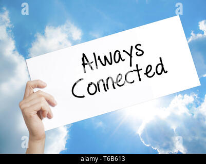 Always Connected Sign on white paper. Man Hand Holding Paper with text. Isolated on sky background. Stock Photo