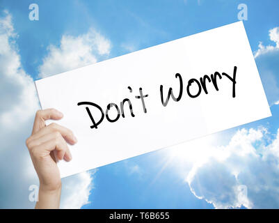 Don't Worry Sign on white paper. Man Hand Holding Paper with text. Isolated on sky background Stock Photo