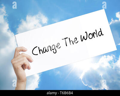 Change The World Sign on white paper. Man Hand Holding Paper with text. Isolated on sky background Stock Photo