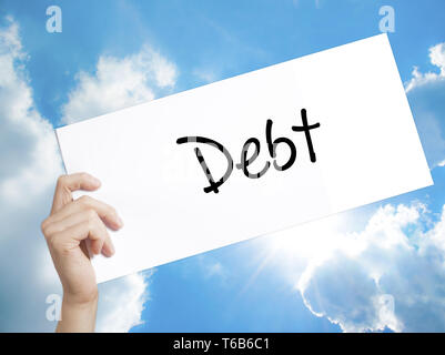 Debt Sign on white paper. Man Hand Holding Paper with text. Isolated on sky background Stock Photo