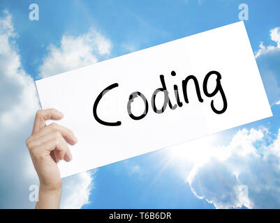 Coding Sign on white paper. Man Hand Holding Paper with text. Isolated on sky background Stock Photo