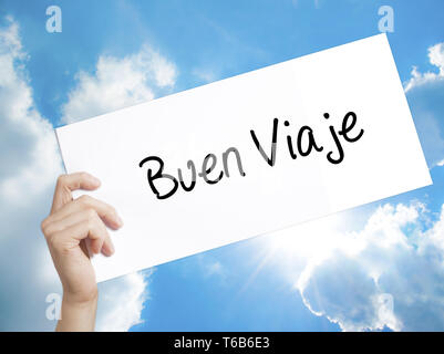Buen Viaje (Good Trip in Spanish) Sign on white paper. Man Hand Holding Paper with text. Isolated on sky background Stock Photo