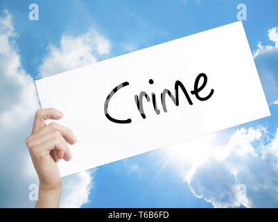 Crime Sign on white paper. Man Hand Holding Paper with text. Isolated on sky background Stock Photo
