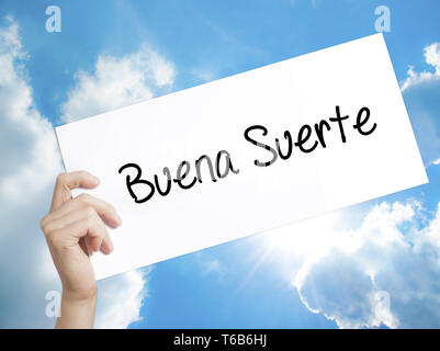 Buena Suerte( Good Luck in Spanish) Sign on white paper. Man Hand Holding Paper with text. Isolated on sky background Stock Photo