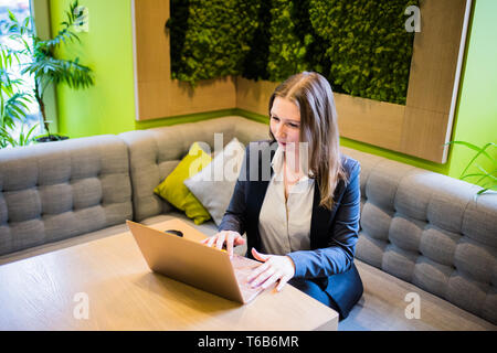 Young business woman working with laptop on the table in the city cafe interior, lady freelancer in coworking Stock Photo