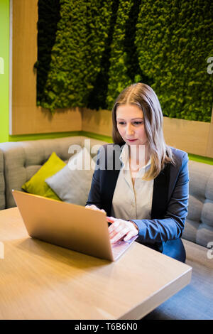 Young business woman working with laptop on the table in the city cafe interior, lady freelancer in coworking Stock Photo
