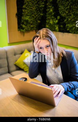 Young business woman working with laptop on the table in the city cafe interior, lady freelancer in coworking Stock Photo