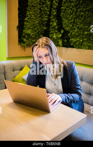 Young business woman working with laptop on the table in the city cafe interior, lady freelancer in coworking Stock Photo