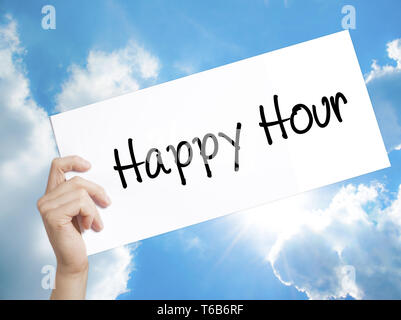 Happy Hour Sign on white paper. Man Hand Holding Paper with text. Isolated on sky background Stock Photo