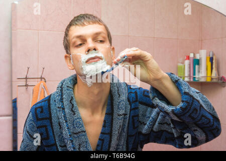 Young guy shaves neck in front of the mirror Stock Photo