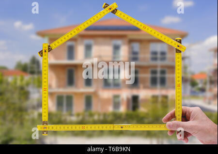shell of house under construction with folding ruler in hand of real estate agent Stock Photo