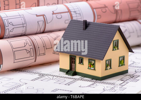 model house standing on architectural construction plans Stock Photo