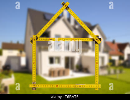 shell of house under construction with folding ruler in hand of real estate agent Stock Photo