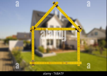 shell of house under construction with folding ruler in hand of real estate agent Stock Photo