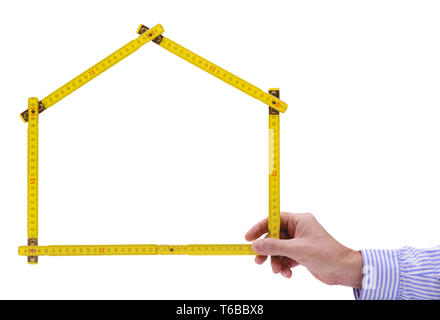 shell of house under construction with folding ruler in hand of real estate agent Stock Photo