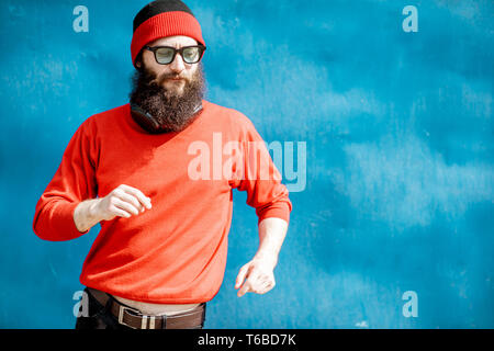 Portrait of a stylish man in red sweater and hat dancing on the colorful background Stock Photo