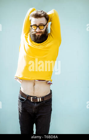 Portrait of a confident stylish bearded man in yellow sweater on the turquoise background outdoors Stock Photo