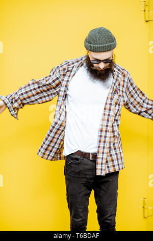 Portrait of a cool stylish man in shirt and hat posing on the bright yellow background Stock Photo