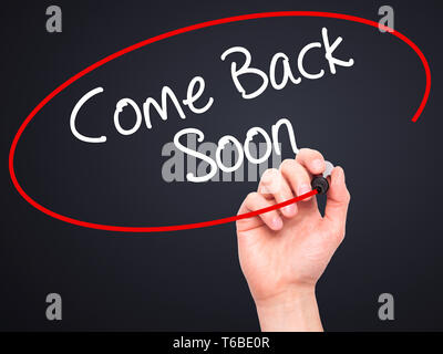 Man Hand writing Come Back Soon with black marker on visual screen. Stock Photo