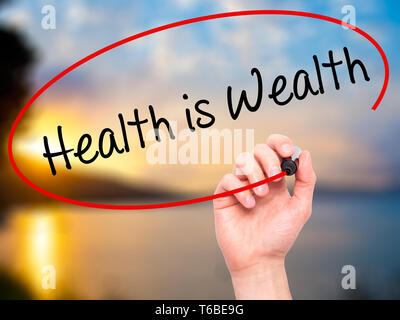 Man Hand writing Health is Wealth with black marker on visual screen Stock Photo