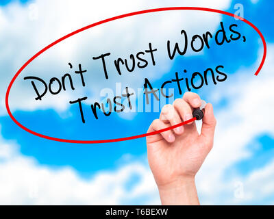 Man Hand writing Don't Trust Words, Trust Actions with black marker on visual screen Stock Photo