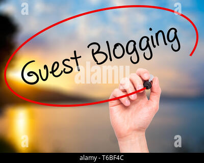 Man Hand writing Guest Blogging  with black marker on visual screen Stock Photo