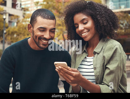 Smiling young couple looking at smartphone Stock Photo