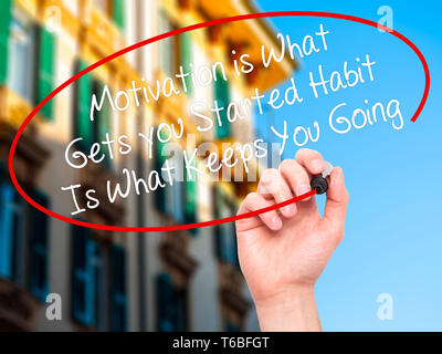 Man Hand writing Motivation is What Gets you Started Habit Is What Keeps You Going with black marker on visual screen Stock Photo