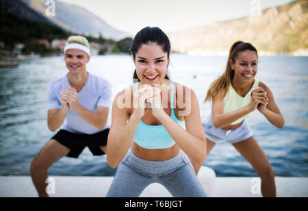 Group of happy friends or sportsmen exercising and stretching outdoor Stock Photo
