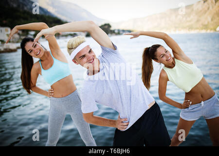 Group of happy friends or sportsmen exercising and stretching outdoor Stock Photo