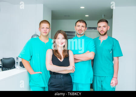 Smiling portrait team in uniform providing healthcare treatment in modern medical centre. Clinic, profession, people, health care and medicine concept Stock Photo