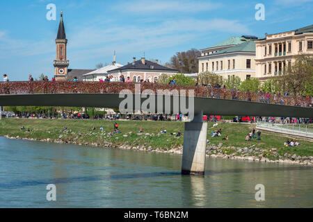 Salzburg Makartsteg, view on a summer day of people walking over the Makartsteg bridge and relaxing along the banks of the Salzach River, Salzburg. Stock Photo