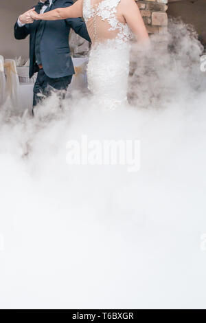 Wedding first dance smoke effect. Bride and groom dancing at wedding party in restaurant. Stock Photo