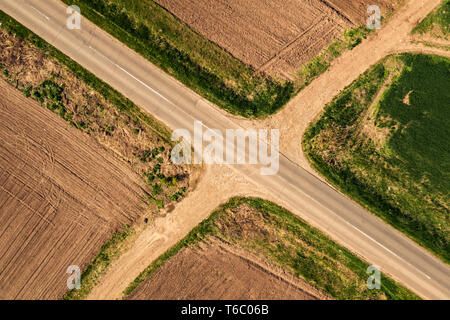 Aerial view of roadway and dirt road intersection, top down from drone pov Stock Photo