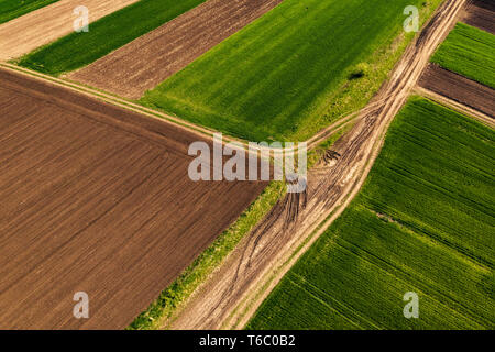 Aerial view of dirt road through countryside and agricultural field from drone pov Stock Photo