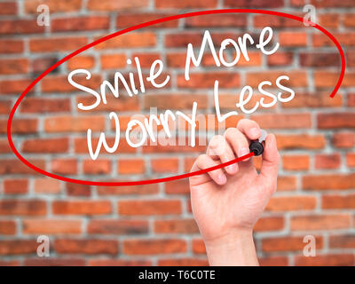 Man Hand writing Smile More Worry Less with black marker on visual screen Stock Photo
