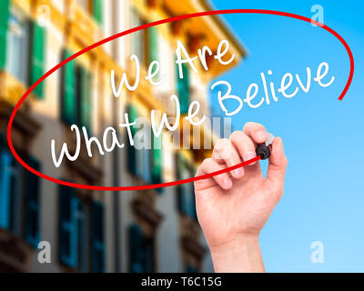 Man Hand writing We Are What We Believe with black marker on visual screen Stock Photo