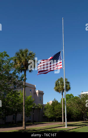 The Stars and Stripes flies at half-staff in Charleston, South Carolina, USA. The flag pole is outside of the old Citadel at Marion Square. Stock Photo