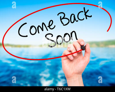 Man Hand writing Come Back Soon with black marker on visual screen. Stock Photo