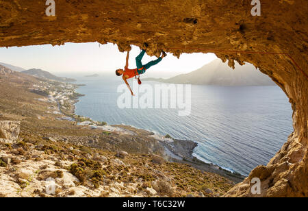 Male rock climber on challenging route going along ceiling in cave, Kalymnos, Greece Stock Photo