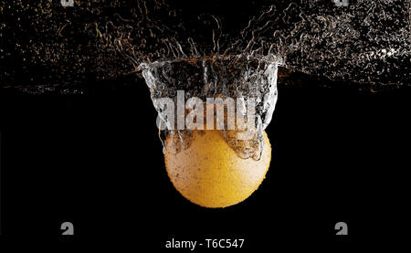 Fruits orange falling into the water with splashes and bubbles. Stock Photo