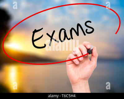 Man Hand writing Exams with black marker on visual screen Stock Photo