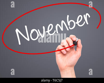 Man Hand writing November with black marker on visual screen Stock Photo