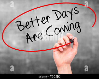 Man Hand writing Better Days Are Coming with black marker on visual screen. Stock Photo