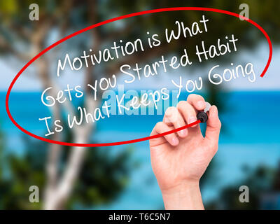 Man Hand writing Motivation is What Gets you Started Habit Is What Keeps You Going with black marker on visual screen Stock Photo