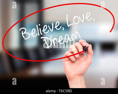 Man Hand writing Believe Love Dream with black marker on visual screen Stock Photo