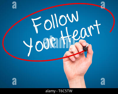 Man Hand writing Follow Your Heart with black marker on visual screen Stock Photo