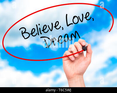 Man Hand writing Believe Love Dream with black marker on visual screen Stock Photo